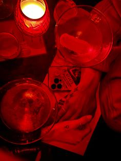 a red light is shining on the table with wine glasses and other things around it