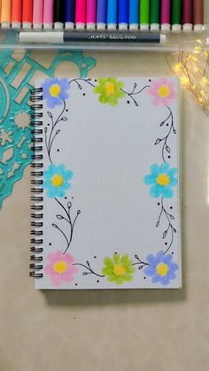 an open notebook with colored markers and crayons on the table next to it