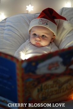 a baby wearing a santa hat is reading a book