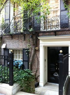 an apartment building with black wrought iron railings and doors on the outside, surrounded by greenery