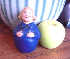 an apple sitting next to a ceramic figurine