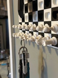 there is a black and white checkered wall with keys hanging from it's hooks