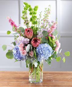 a vase filled with lots of flowers on top of a wooden table