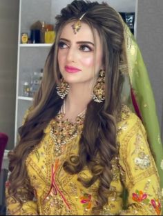 a woman with long hair wearing a yellow dress and gold jewelry is posing for the camera