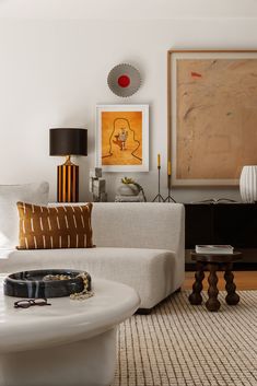 a living room filled with furniture and art on the wall next to a coffee table