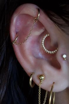 three different types of ear piercings with chains and pearls on the side of them