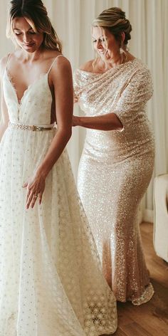 two women in dresses standing next to each other and one is wearing a dress with sequins on it