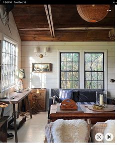 a living room filled with furniture next to two windows and a wooden table in front of it