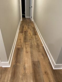 an empty hallway with hard wood flooring and white trim on the walls is shown