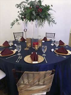 a blue table cloth with place settings and silverware on it is set for a formal dinner