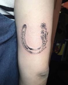 a tattoo on the arm of a person with a horseshoe and flowers in its center