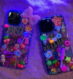 two cell phones are covered with various items on a purple carpet, one is laying down and the other is lying down