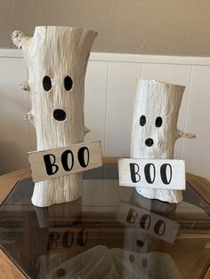 two toilet paper roll ghost decorations sitting on top of a glass table next to each other