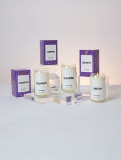 three candles are sitting next to each other in front of boxes on a white surface