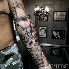 a man's arm with a pirate ship and skull tattoo on the left side of his body