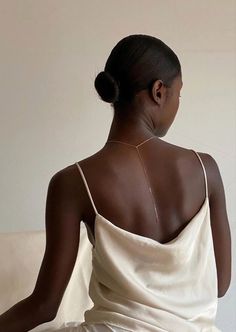 a woman sitting on top of a couch wearing a white dress and holding a cell phone in her hand