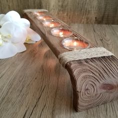 a wooden candle holder with six lit candles on it next to a white orchid flower