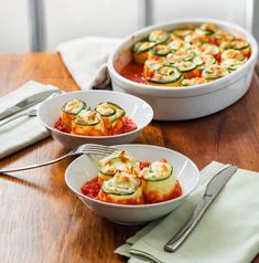 two white bowls filled with food sitting on top of a wooden table next to silverware