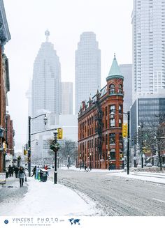 people are walking down the street in front of some tall buildings on a snowy day