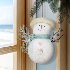 a snowman ornament hanging from the side of a wooden window sill