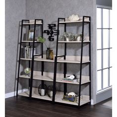 a book shelf with three shelves on each side and various items on the top, in front of a gray wall