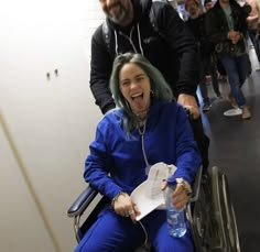 a woman in a wheel chair with her mouth open and tongue out as she sits next to a man