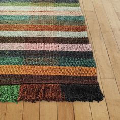 a multicolored rug with fringes on the floor next to a wooden floor