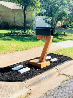 a mailbox sitting in the middle of a flower bed with grass and rocks around it