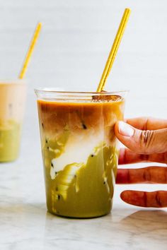 two cups with drinks in them sitting on a white counter top next to each other