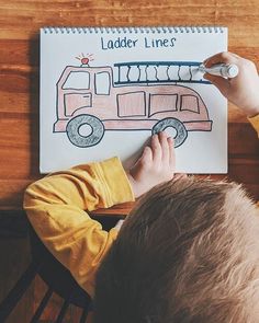 a young boy is drawing a firetruck on paper