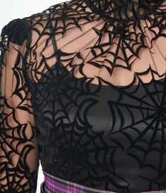 A darling 1960s style high-neck blouse crafted in a lightweight sheer black boasting black flocked spiderwebs throughout. Complete with a ruffle trim on the front, shoulders and neck.Cami Sold SeparatelyAvailable in sizes XS-5X while supplies last.