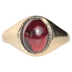 Sat proud upon a gorgeous glossy 9ct yellow gold band is an equally glossy garnet cabochon stone. The stone nearly spans the whole width of this ring. Made in Birmingham 1964, England. Ring Size: M 1/2 or 6 1/2 Band Width At Widest: 11mm Weight: 3.2g Formal Domed Signet Ring With Cabochon, Classic Yellow Gold Signet Ring With Cabochon, Classic Red Oval Cabochon Signet Ring, 14k Gold Oval Cabochon Gemstone Signet Ring, 14k Gold Domed Signet Ring With Gemstone, Classic 14k Gold Signet Ring With Cabochon, Classic Domed Cabochon Signet Ring, Formal Hallmarked Oval Cabochon Signet Ring, Classic Yellow Gold Cabochon Ruby Ring