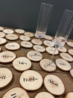 two wine glasses sitting on top of wooden slices with names engraved on the wood slice