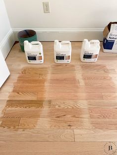 three bottles of paint sitting on top of a wooden floor