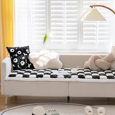 a white couch with pillows on it in front of a window and a floor lamp