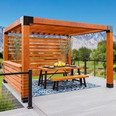 an outdoor dining area with wooden furniture and mountains in the background