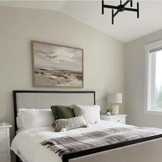 a bedroom with a bed, dresser and window in the corner that has a painting on the wall above it