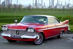 an old red car parked in a parking lot