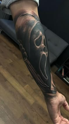 a man's arm with a black and grey tattoo design on the left forearm