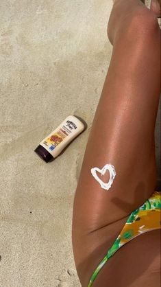 a woman laying on the beach with sunscreenr next to her leg and arm