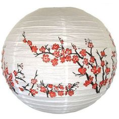 a white paper lantern with red flowers painted on the bottom and black branches around it