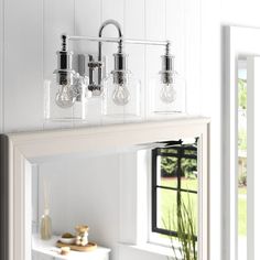 a bathroom vanity with three lights and a mirror on the wall next to a fireplace