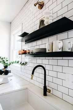 black and white kitchen with open shelving on the wall, brass faucet