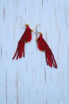 red bird beaded earrings on white wooden background