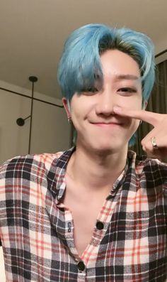 a young man with blue hair making a funny face while holding his finger to his nose