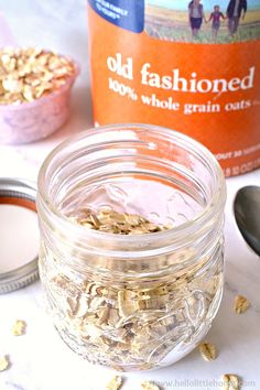 a jar filled with oatmeal sitting on top of a table next to a spoon