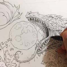 someone is drawing an image on paper with a pen and inking it in the shape of a fish