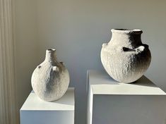 two white vases sitting on top of each other