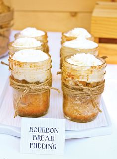 mason jars filled with whipped cream sitting on top of a white tray next to wooden boxes