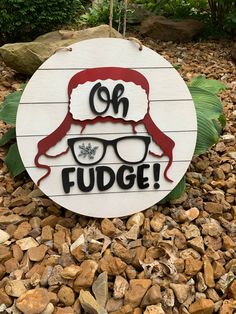 a sign that says fudge with glasses on it in front of rocks and plants